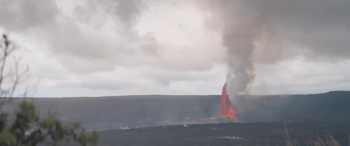 A volcanic eruption produces a thick plume of smoke on a cloudy day