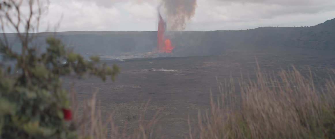 A volcanic eruption produces a thick plume of smoke on a cloudy day