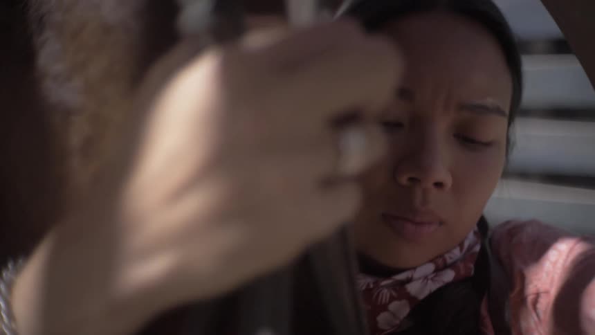 A person holds a horses head close touching its face while adjusting a bridle gently