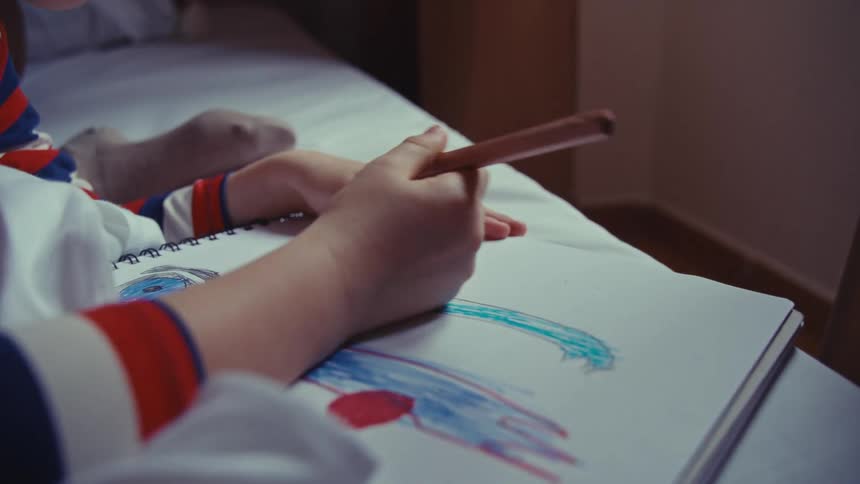A child draws while in bed