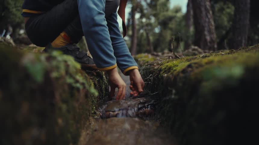 Person placing a twig on a small river path in the forest