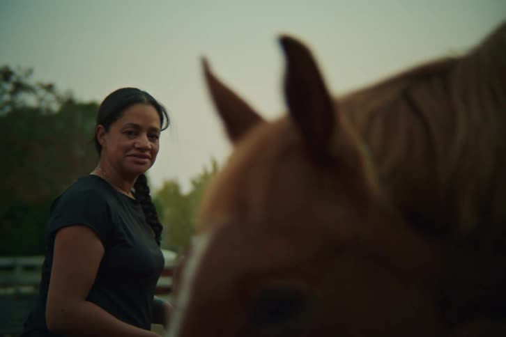Woman next to a brown horse outdoors