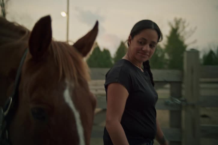 Woman walking through a rural area next to a horse