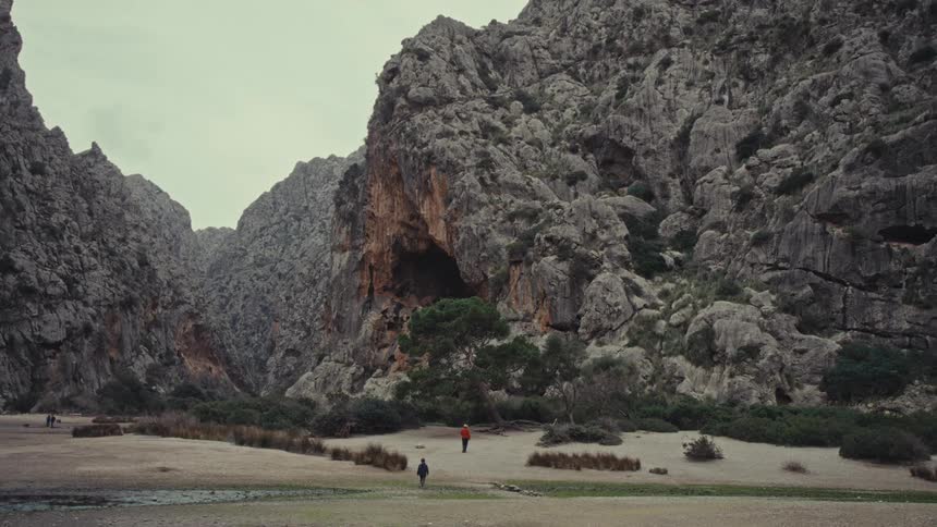Two people walking in a natural environment with rocky mountains