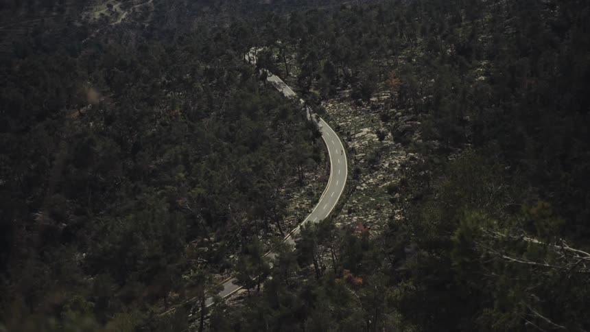 Top view of a highway surrounded by dense forest
