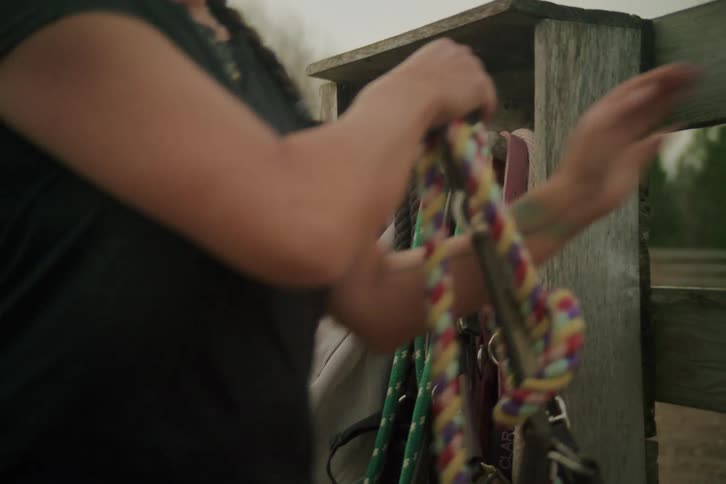 Woman picking up ropes on a wooden ranch
