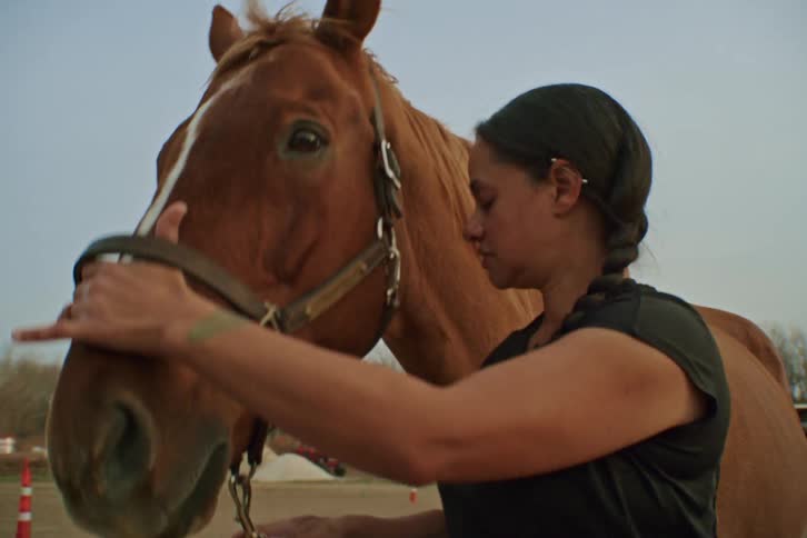 A woman is holding the harness of a horse