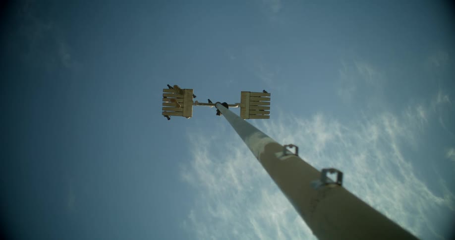 Upward view of a large antenna against a blue sky with few clouds