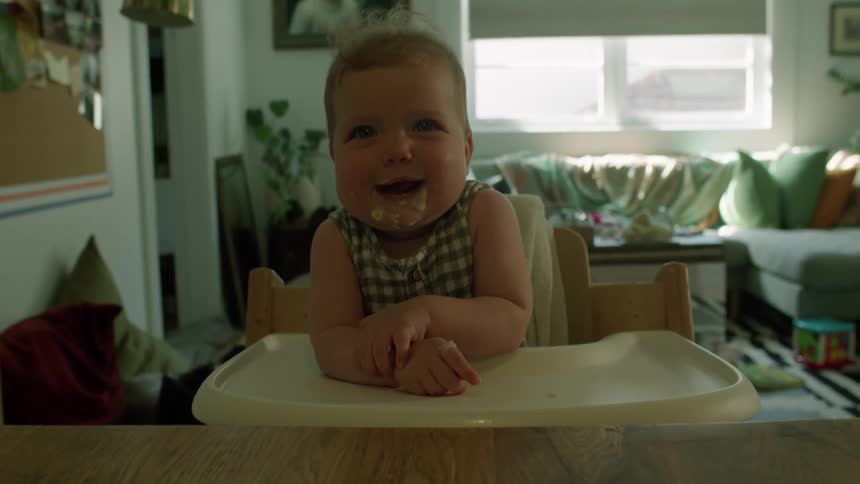 A baby with food on her face laughs