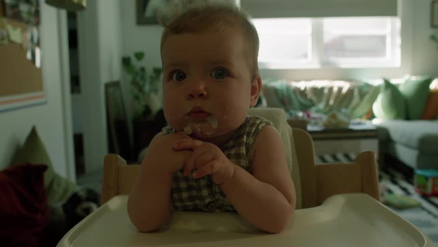 Baby with dirty mouth sitting in a highchair