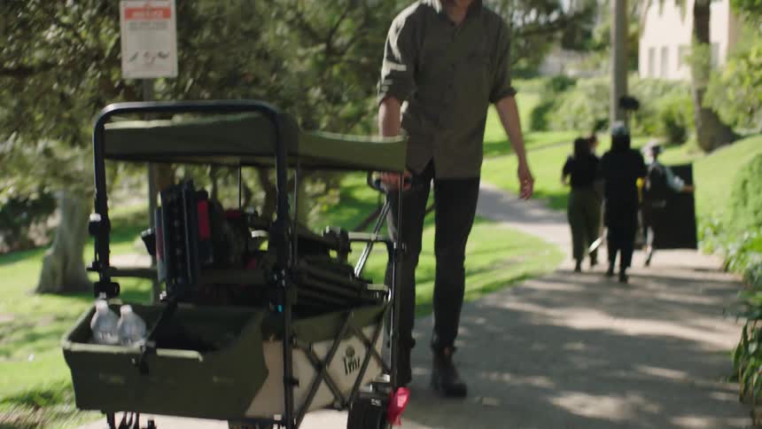A man pulls a wagon of film equipment