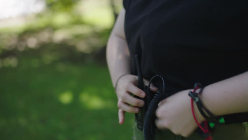 A woman puts a walkie talkie on her belt