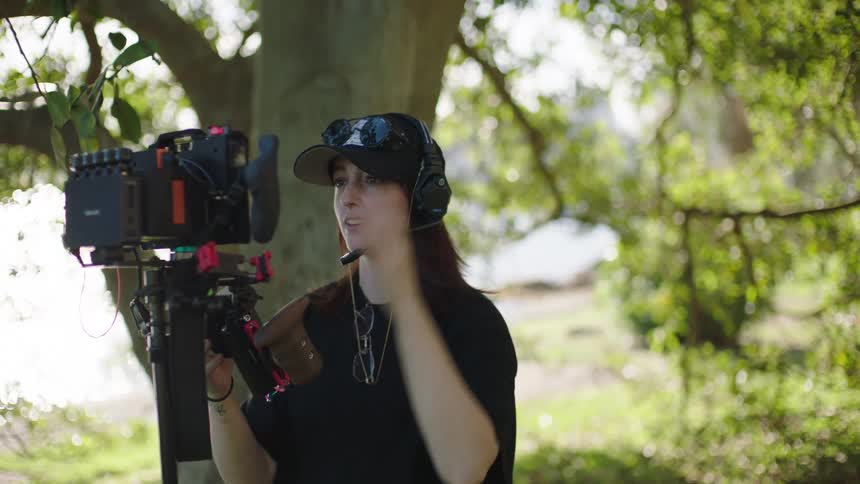 Woman filmmaker driving a professional video camera and arranging its microphone point