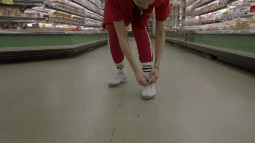 Woman ties her shoe in the middle of a grocery store aisle