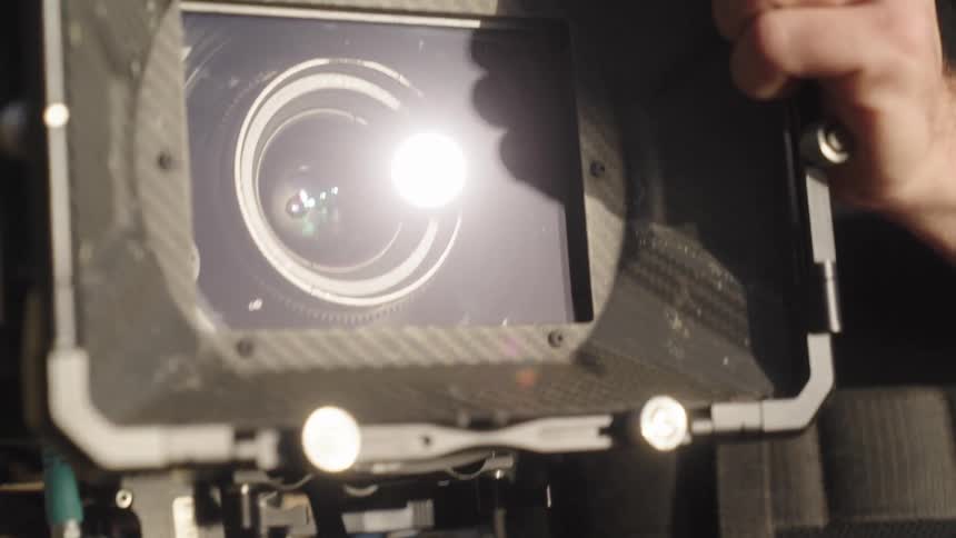 Close up of a hand handling the lens of a professional video camera