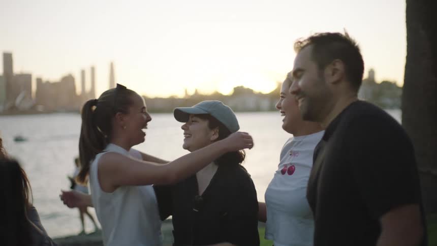 Group of happy people outdoors by a lake hugging each other