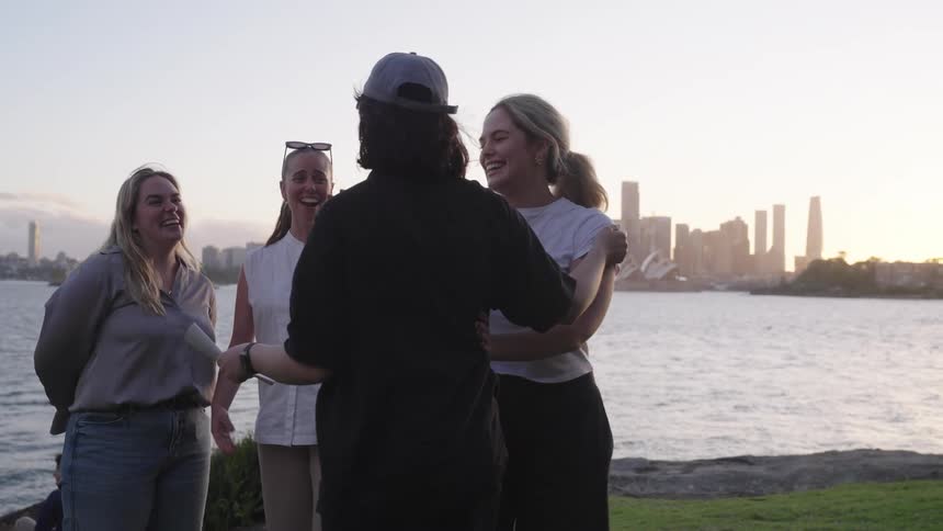 Women hugging each other happily by a lake