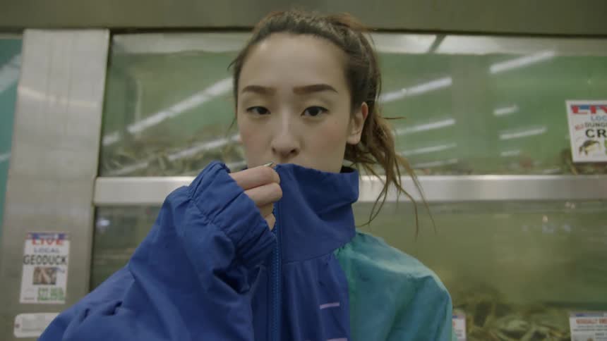 Woman zipping up her coat standing in front of crab tanks