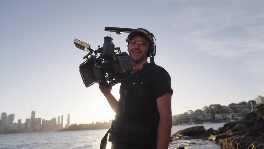 A man holding a large camera smiles