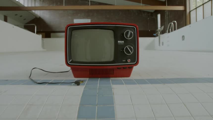 A small, red tv is sitting in an empty pool