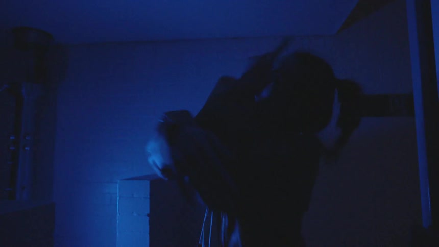 Woman dances interpretively in the dark with blue light flashing