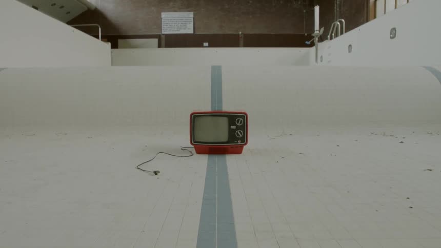 Tv on the floor of an empty indoor pool
