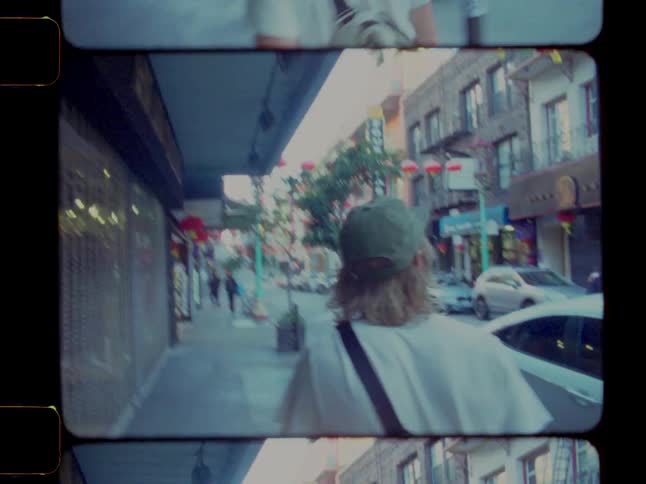 View of a man from behind wearing a cap walking through the city