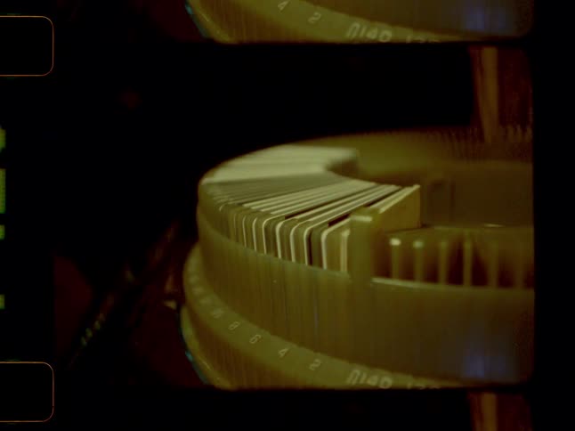 Displayed within a the numbered slots of a slide projector carousel holding slides