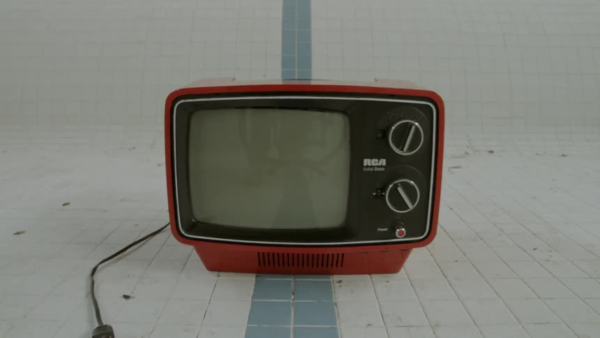 Tv on the floor of an empty indoor pool
