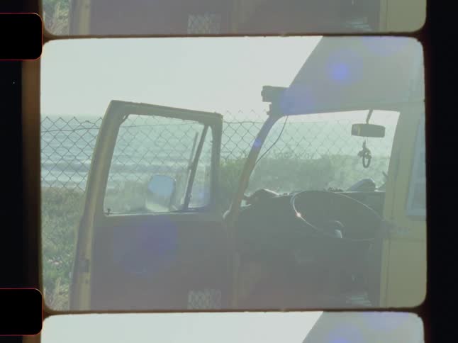 The interior of a vehicle with an open door revealing a glimpse of a chain link fence and possibly a body of water in the background