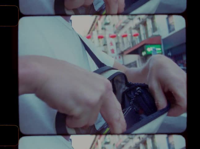 Man taking a camera out of a bag while on the streets of a city