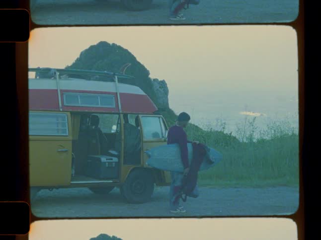 Man taking a surfboard in a yellow van outdoors