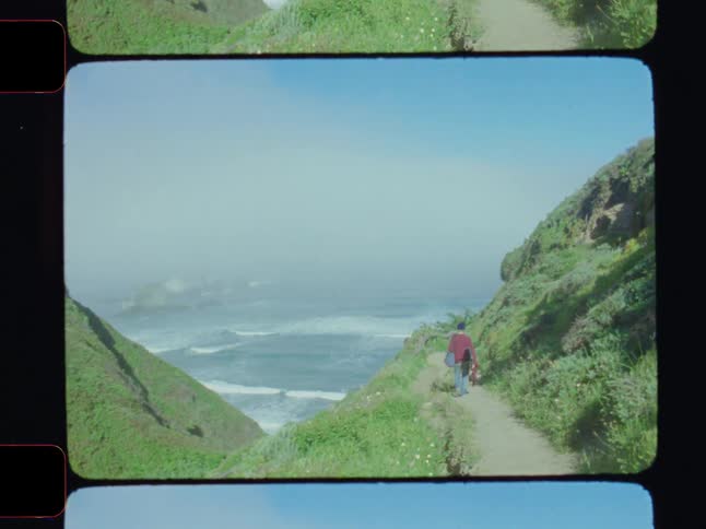 A man walks on a trial on the cliff by the shore