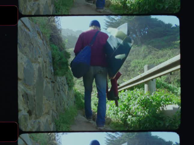 Man with a surfboard walking down a trail