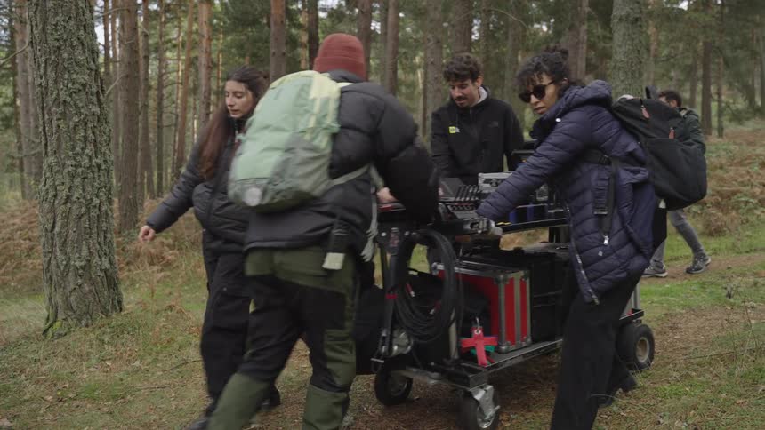 Film makers push a cart of equipment into the woods