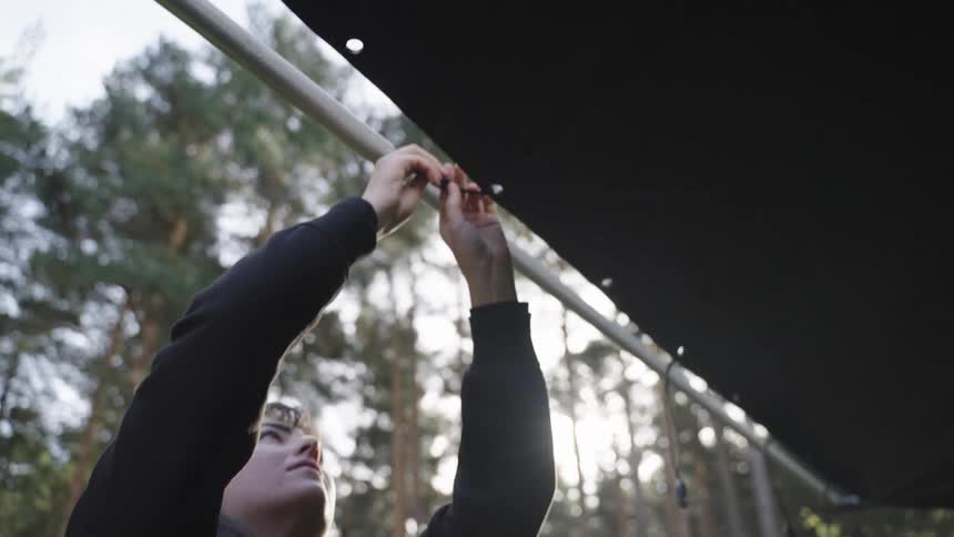 A woman is tying rope on the tent