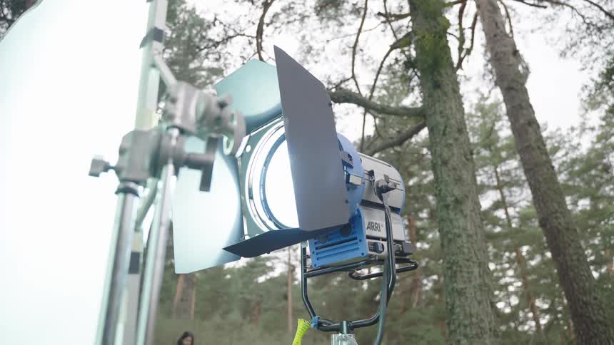 Studio lighting shining light against a white screen outdoors surrounded by trees