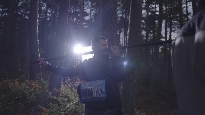 A member of the film crew is operating a boom microphone