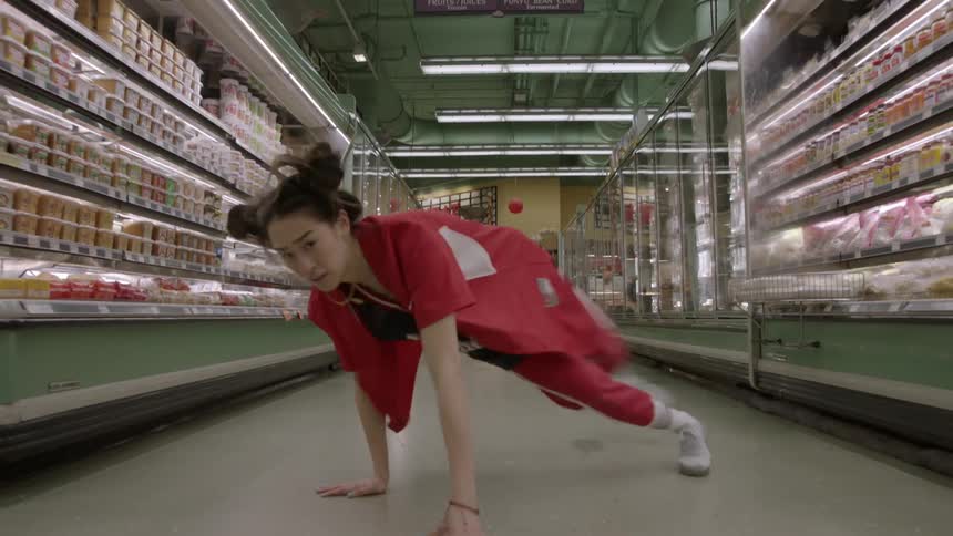 Woman dancing on the floor of a grocery store aisle