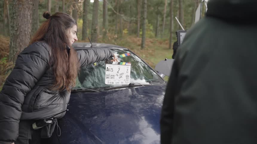 A woman uses a clapboard to start filming a scene