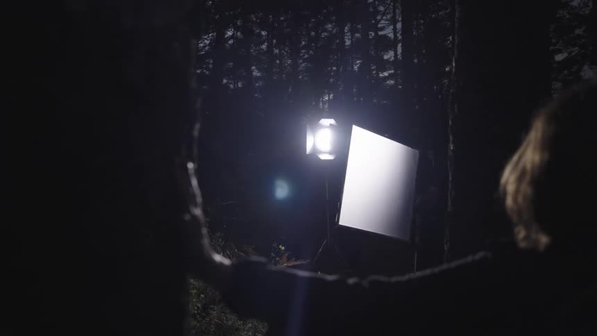 A film crew are filming in the woods at night
