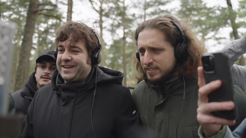 Group of male filmmakers enjoying an outdoor scene on an electronic device