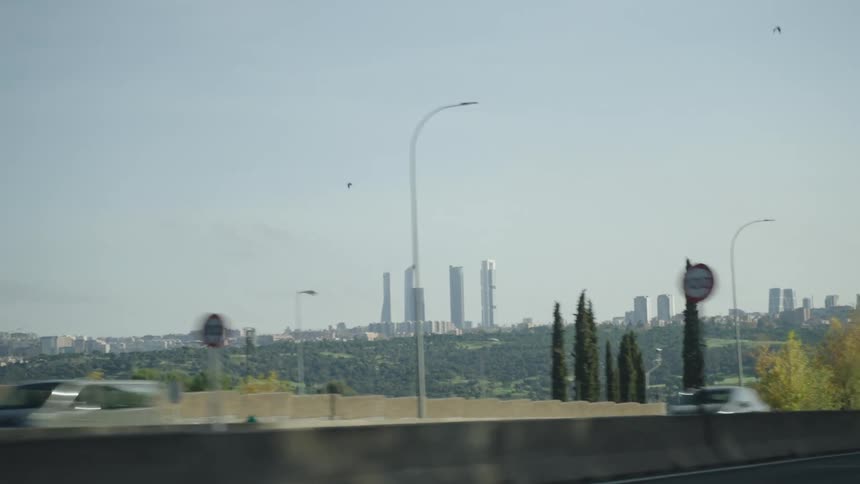 Vehicles drive down a highway near a metropolis on a sunny autumn day