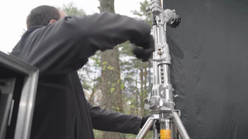 A man is turning the handle on the tripod