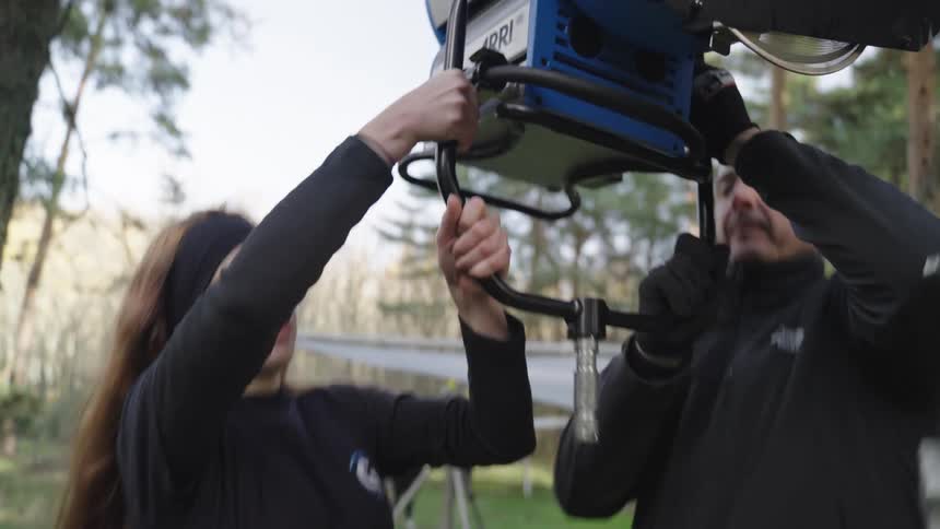 Two people are setting up lights on a film shoot