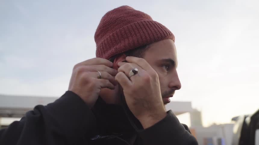 Man outdoors putting an accessory in his ear