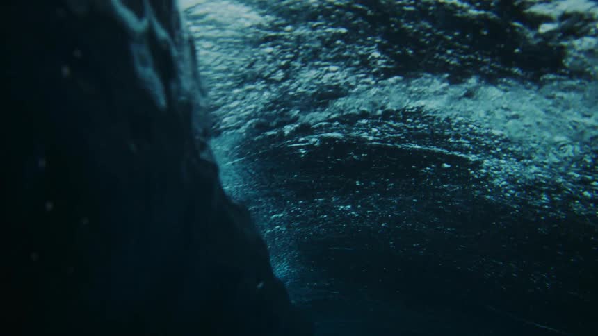 A man surfs on a large wave in dark blue water