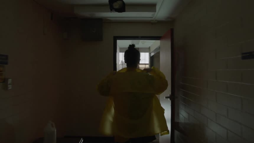 Woman walks down a dark hallway out the door