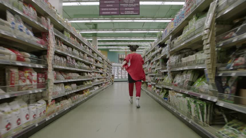 Woman walks down the aisle of a grocery store