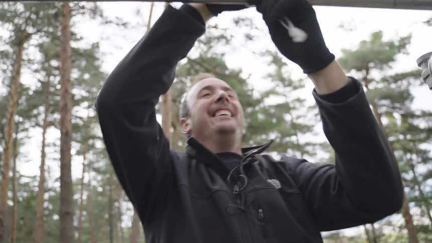 A man is setting up film equipment in the forest